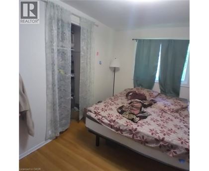 A bedroom with a bed, a lamp, and a window with curtains.