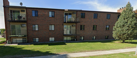 A red brick building with a green lawn in front.