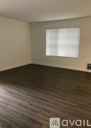 A room with wooden flooring and a window with blinds.