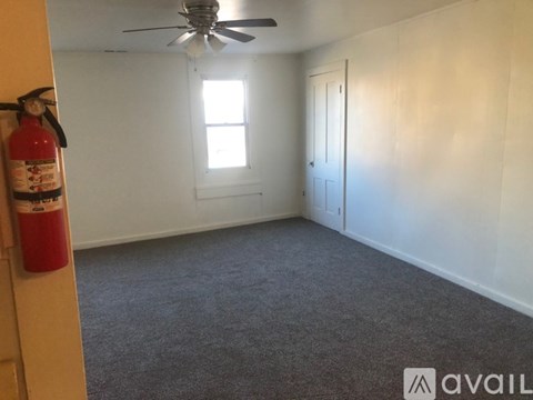 A room with a fire extinguisher on the wall and a ceiling fan.