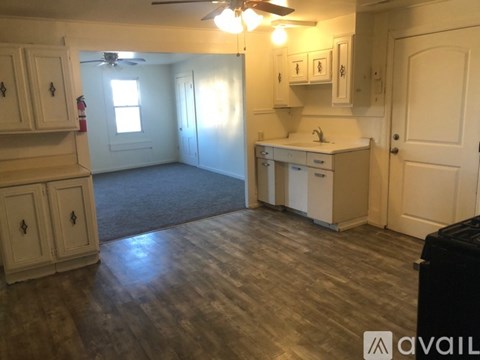 A kitchen with white cabinets and a wooden floor.
