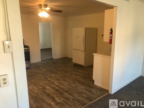 A room with a fan, a fridge, and a fire extinguisher.