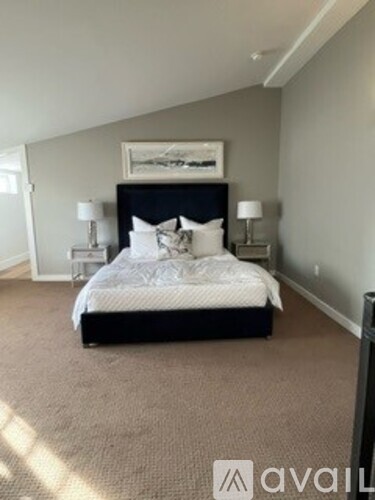 A bedroom with a large bed and two lamps.
