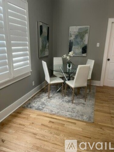 A dining room with a glass table and white chairs.