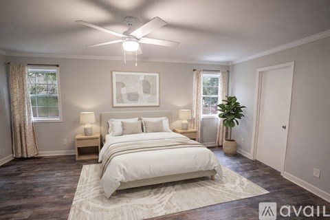 A bedroom with a large bed, a ceiling fan, and a rug on the floor.
