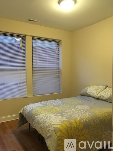 A bedroom with a bed and a window with blinds.