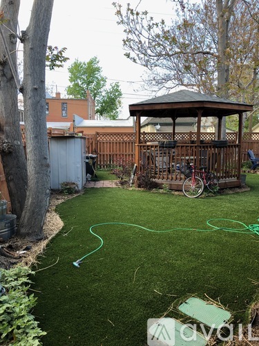 A backyard with a gazebo and a hose.