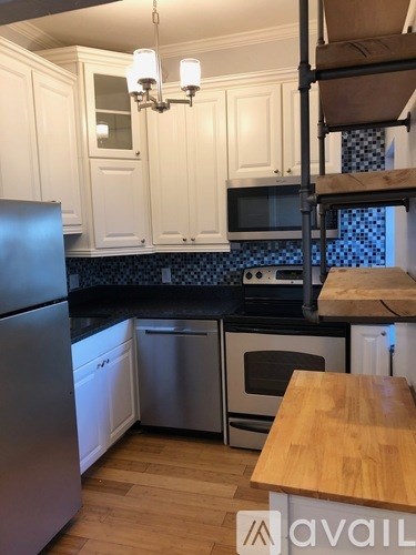 A kitchen with white cabinets and a wooden island.