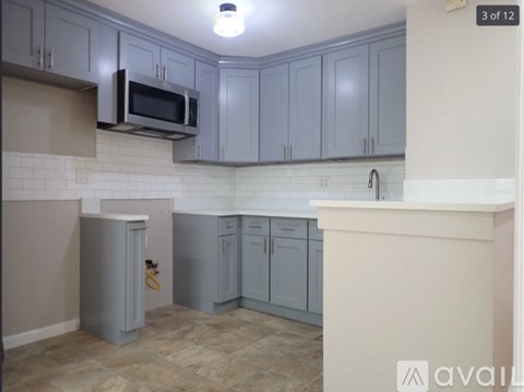 A kitchen with grey cabinets and a white counter.
