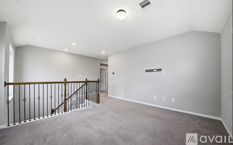 A spacious room with a carpeted floor and a staircase with a wooden railing.