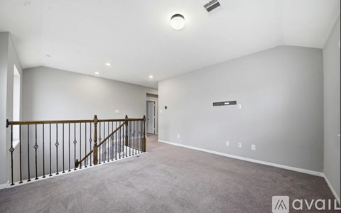 A spacious room with a carpeted floor and a staircase with a wooden railing.