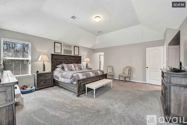A bedroom with a large bed and a window with blinds.