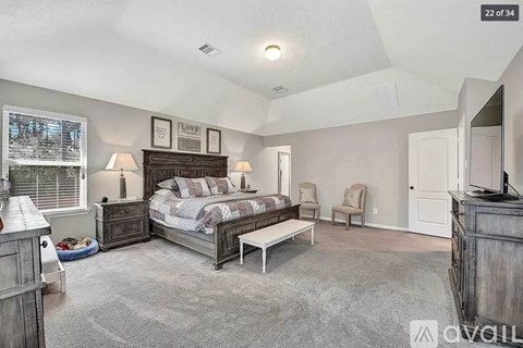 A bedroom with a large bed and a window with blinds.