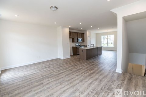 A spacious living room with a kitchen area in the background.