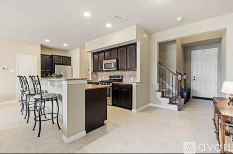 A modern kitchen with dark brown cabinets and a white island.