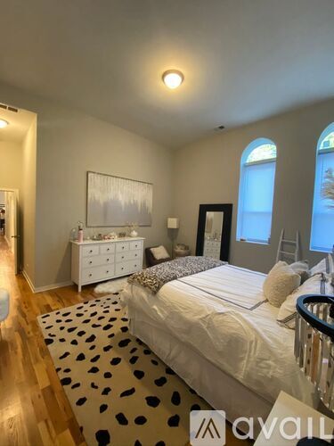A bedroom with a bed, dresser, and a painting on the wall.