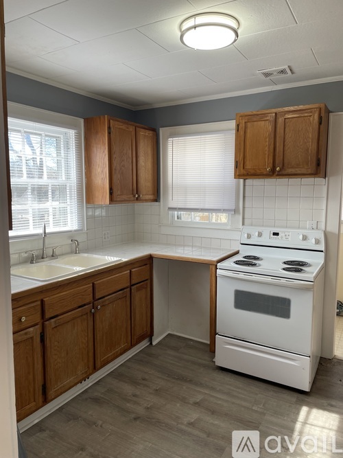 A white stove is in a kitchen with wooden cabinets.
