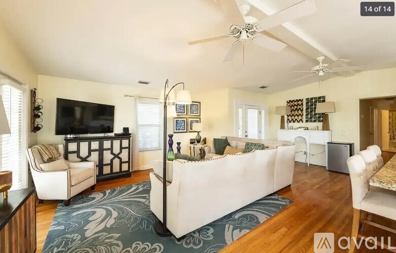 A living room with a white couch and a television on the wall.