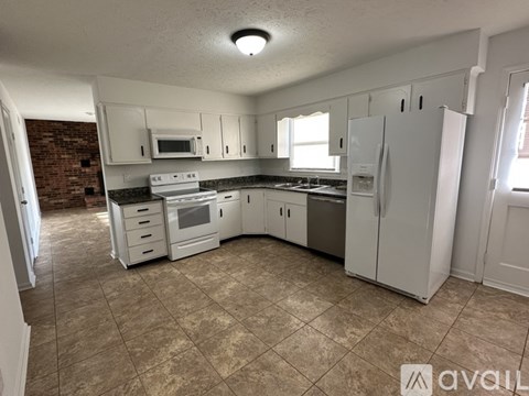 A kitchen with white appliances and cabinets.