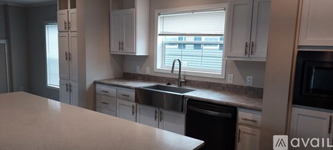A kitchen with a sink and a window with blinds.