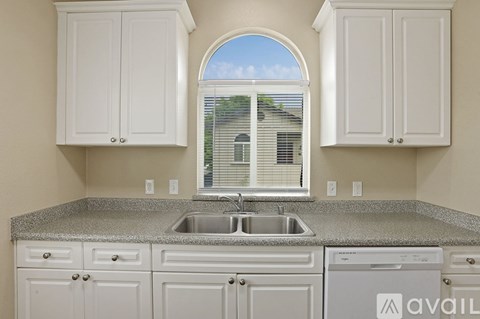 A kitchen with white cabinets and a granite countertop.