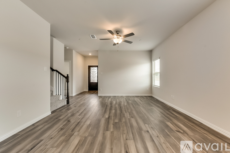 A spacious room with wooden flooring and a ceiling fan.