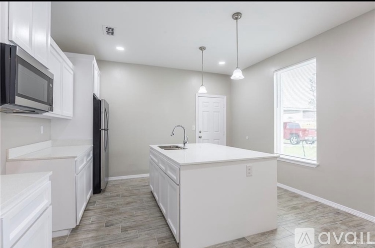 A kitchen with white cabinets and a black refrigerator.