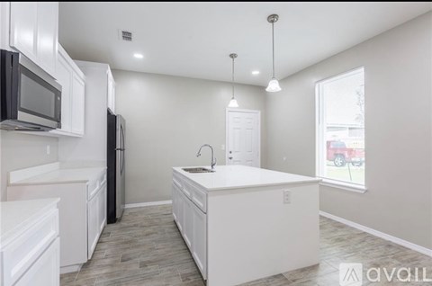 A kitchen with white cabinets and a black refrigerator.