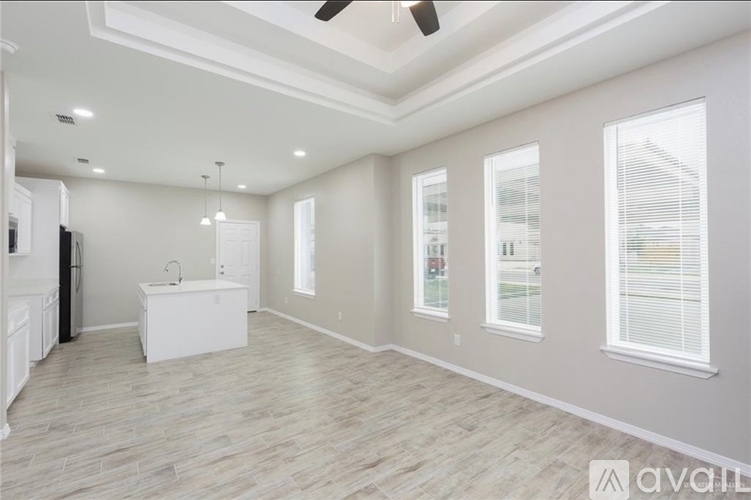A spacious room with a kitchenette and a ceiling fan.