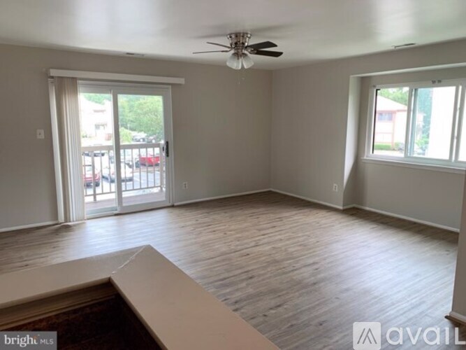 A spacious room with a ceiling fan and sliding glass doors leading to a balcony.