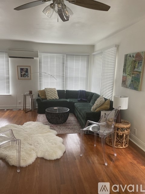 A living room with a green couch and a white rug.