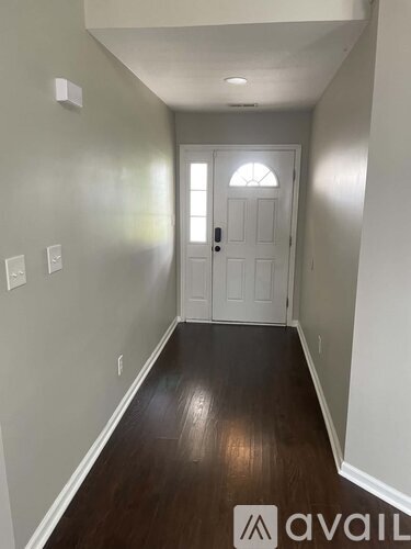 A hallway with a white door and wooden floor.