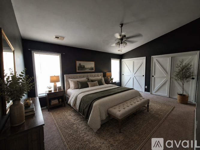 A bedroom with a large bed, a ceiling fan, and a rug on the floor.