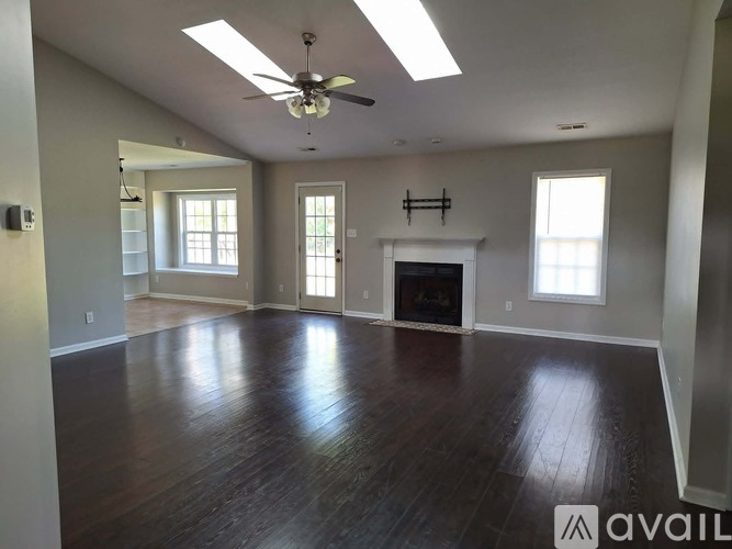 A spacious living room with wood flooring and a fireplace.