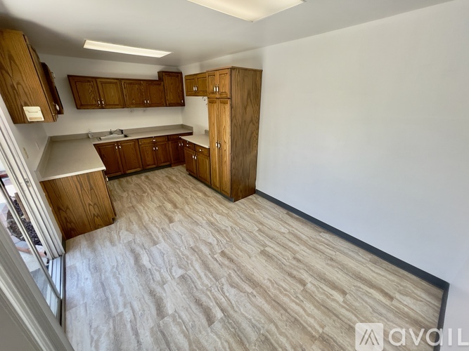 A kitchen with wooden cabinets and a white wall.