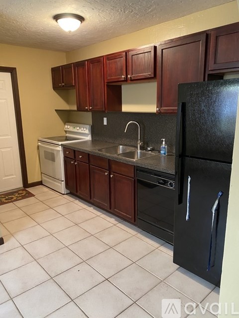 A kitchen with a black refrigerator, white oven, and brown cabinets.