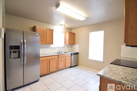 A kitchen with a stainless steel refrigerator and wooden cabinets.