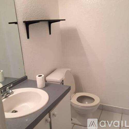 A bathroom with a toilet, sink, and toilet paper roll.