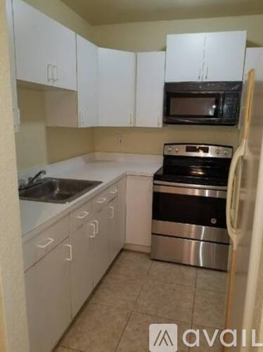 A kitchen with white cabinets and a black microwave.