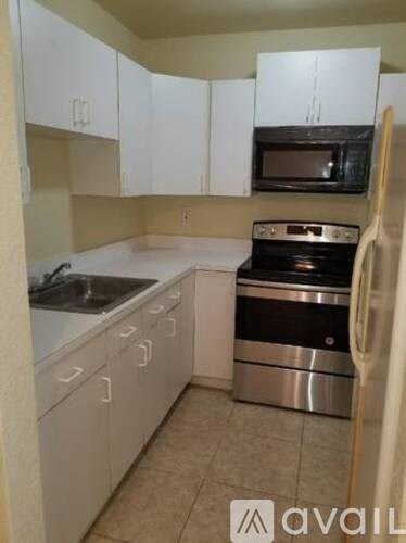 A kitchen with white cabinets and a black microwave.