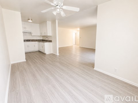 A spacious living room with a ceiling fan and lighting fixture.