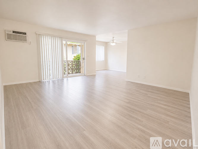 A spacious room with light wood flooring and white walls.
