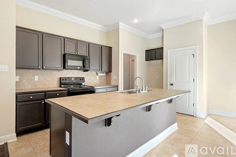 A kitchen with a brown countertop and black cabinets.