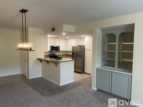 A kitchen with a refrigerator, microwave, and a counter with a sink.