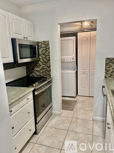 A kitchen with white cabinets and a black microwave.