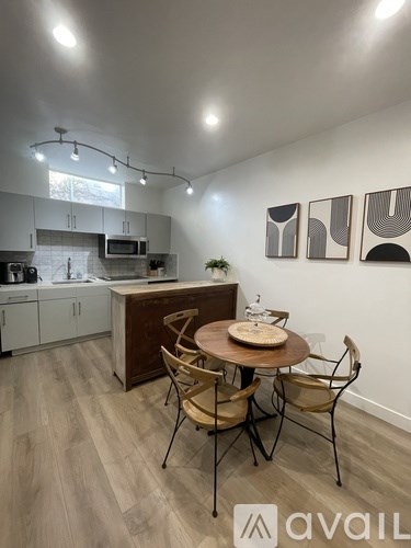 A kitchen with a table and chairs in the foreground and a plant on the counter.