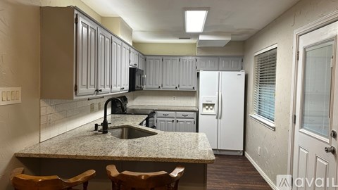A kitchen with a sink, refrigerator, and cabinets.