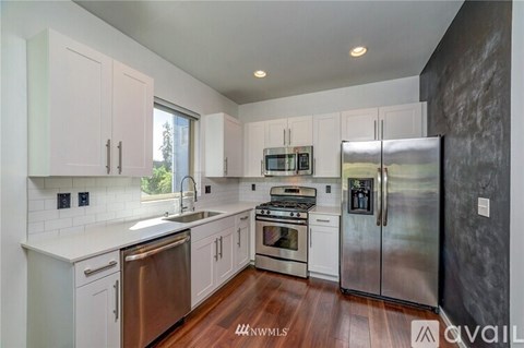 A modern kitchen with white cabinets and stainless steel appliances.