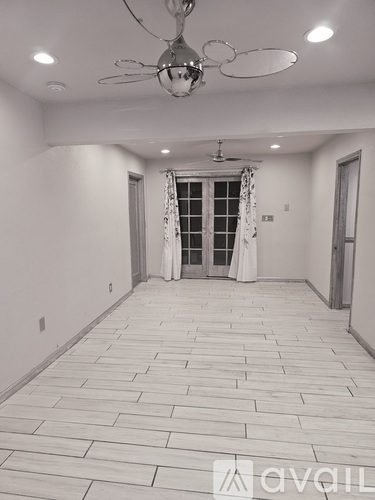 A spacious room with a ceiling fan and a doorway leading to another room.