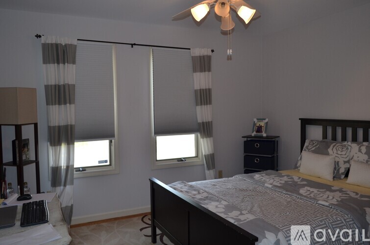 A bedroom with a bed, dresser, and window with curtains.